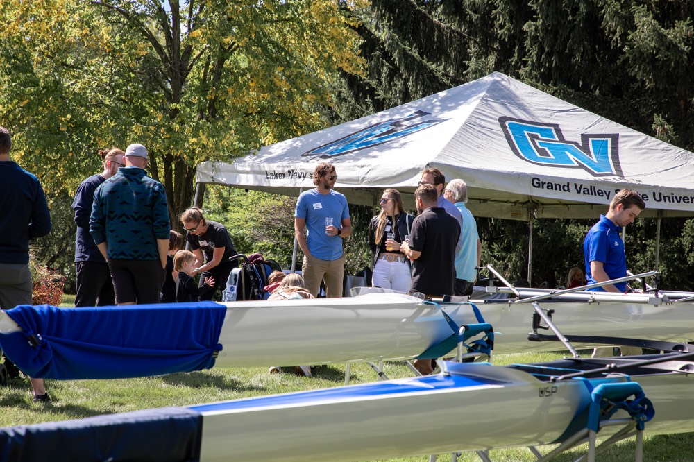 People outside mingling with each other under GVSU tents and boats